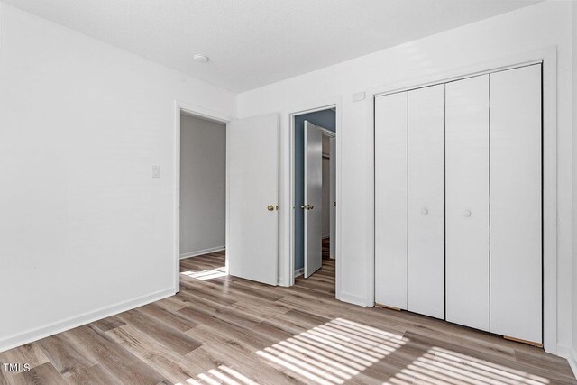 14 Stone Village Ct, Durham, NC 27704 - unfurnished bedroom featuring light wood finished floors, a closet, and baseboards