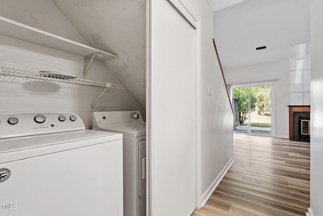 clothes washing area featuring washer and dryer, a textured ceiling, and light wood-type flooring