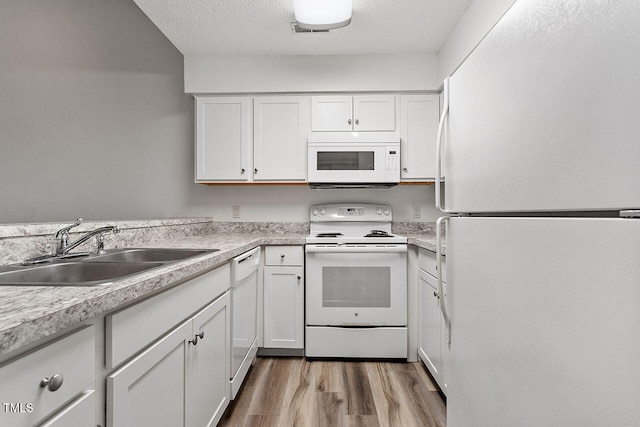 kitchen with white cabinetry, sink, and white appliances