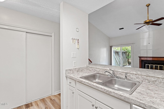 kitchen with white cabinetry, a textured ceiling, sink, light hardwood / wood-style floors, and ceiling fan