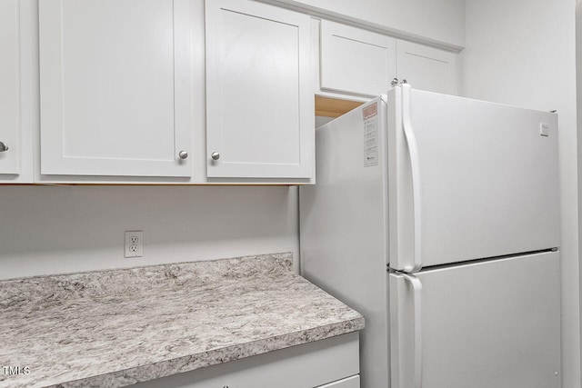 kitchen featuring white cabinets and white fridge