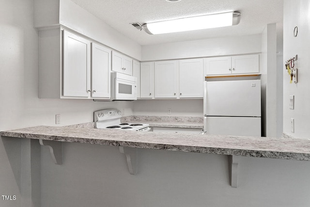 kitchen featuring kitchen peninsula, a kitchen breakfast bar, a textured ceiling, white appliances, and white cabinets