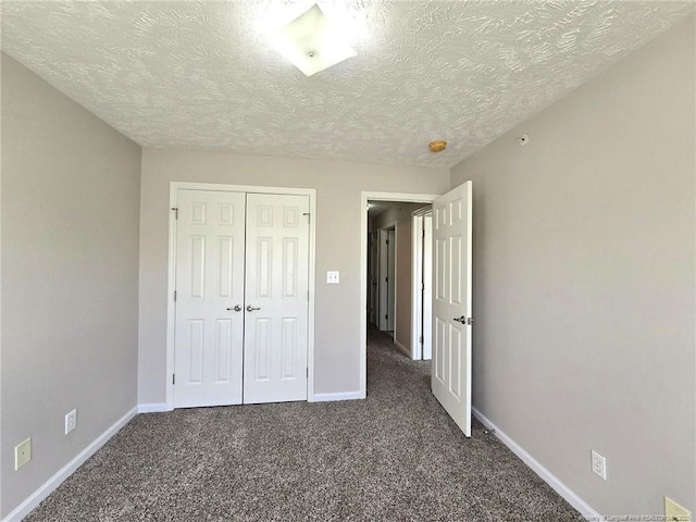 unfurnished bedroom with a closet, dark carpet, and a textured ceiling