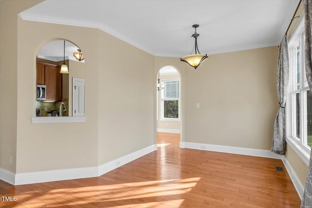 unfurnished room featuring ornamental molding, a wealth of natural light, and light hardwood / wood-style flooring