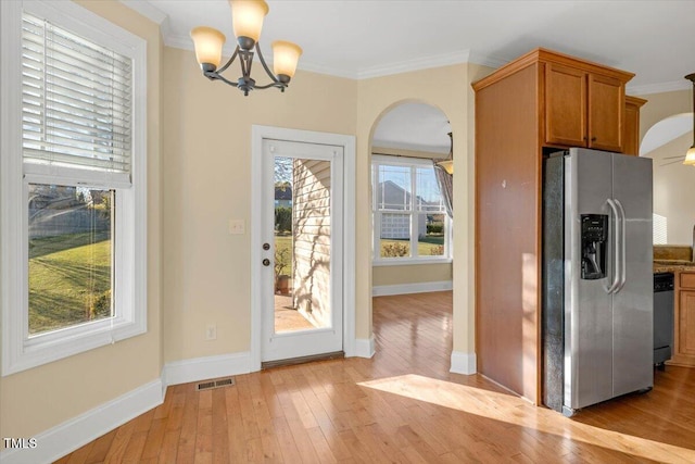 doorway with crown molding, a healthy amount of sunlight, and light wood-type flooring