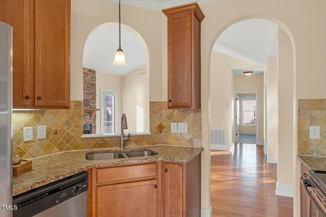 kitchen featuring hanging light fixtures, sink, light hardwood / wood-style flooring, light stone countertops, and appliances with stainless steel finishes