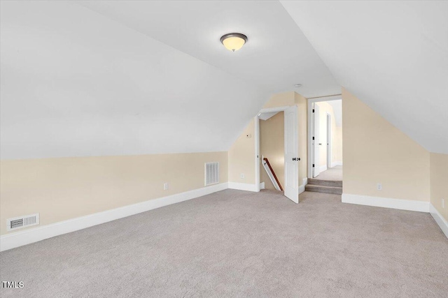 additional living space featuring light colored carpet and lofted ceiling