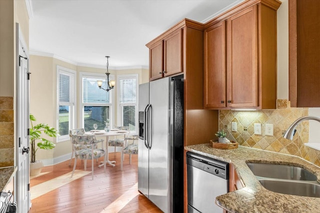 kitchen with appliances with stainless steel finishes, light hardwood / wood-style floors, light stone counters, and sink