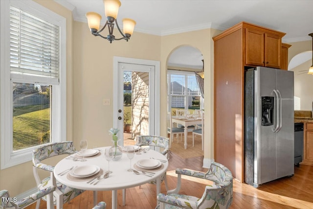 dining area featuring plenty of natural light, ornamental molding, and light wood-type flooring