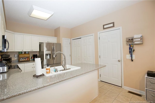 kitchen featuring sink, light stone countertops, light tile patterned floors, white cabinetry, and stainless steel appliances