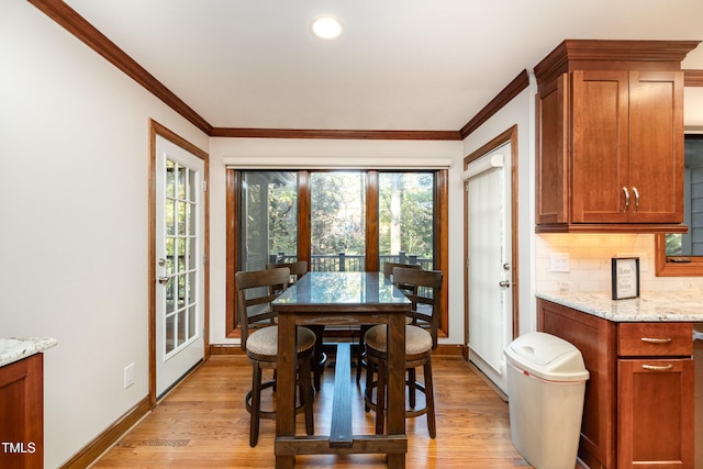 dining space with crown molding, light hardwood / wood-style flooring, and french doors