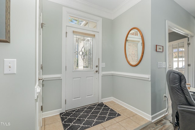 foyer entrance with light tile patterned floors and crown molding