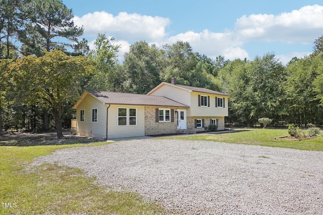 1379 Juniper Lake Rd, West End, NC 27376 - tri-level home with a front yard, driveway, brick siding, and view of wooded area