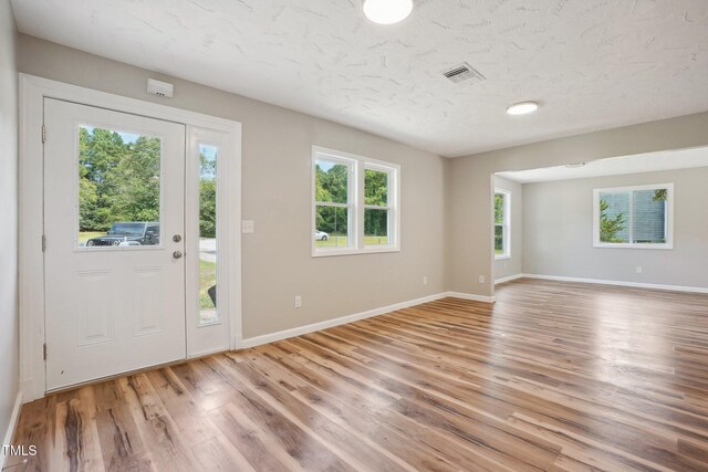 entryway with a textured ceiling, light hardwood / wood-style floors, and a healthy amount of sunlight