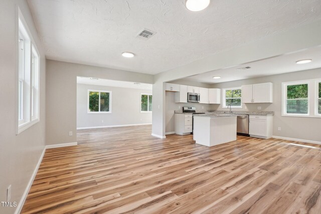 kitchen featuring white cabinets, sink, a kitchen island, light wood-type flooring, and appliances with stainless steel finishes