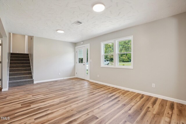 spare room featuring light wood-type flooring and a textured ceiling