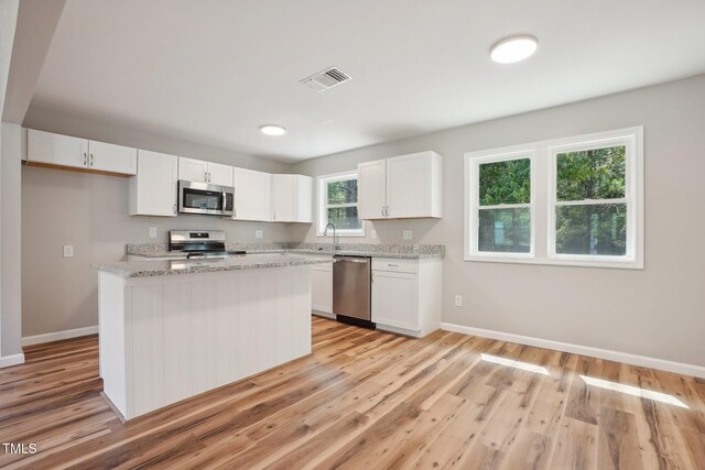 kitchen featuring white cabinetry, appliances with stainless steel finishes, light stone countertops, and light hardwood / wood-style floors