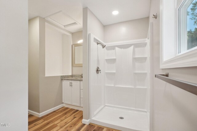 bathroom with hardwood / wood-style flooring, vanity, and walk in shower