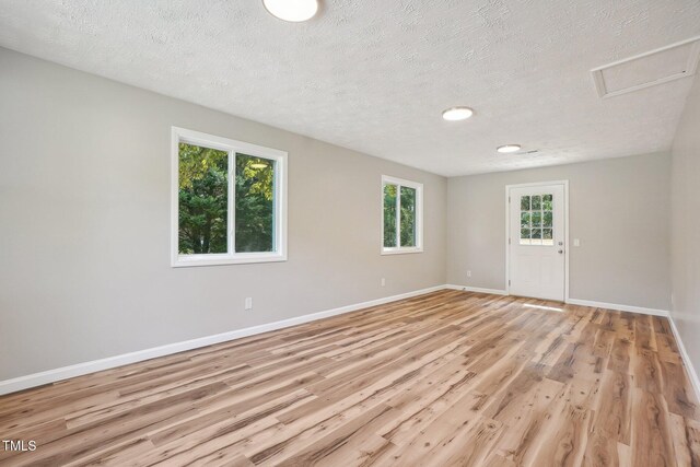 empty room featuring a textured ceiling and light hardwood / wood-style flooring