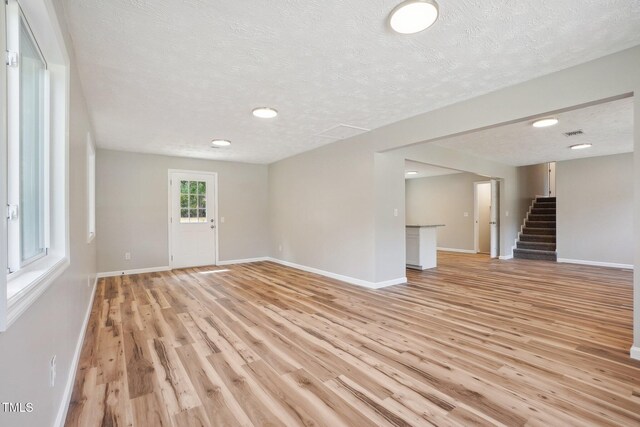 unfurnished living room featuring light wood-type flooring and a textured ceiling