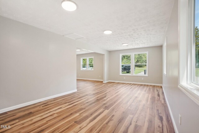 unfurnished room with a textured ceiling and light hardwood / wood-style floors