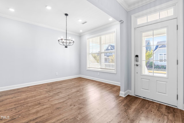 foyer entrance featuring dark wood-type flooring, crown molding, and a notable chandelier