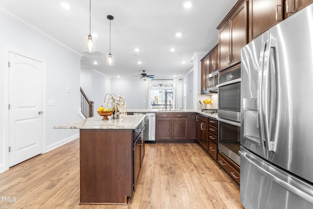 kitchen featuring ceiling fan, a center island, hanging light fixtures, stainless steel appliances, and light stone counters