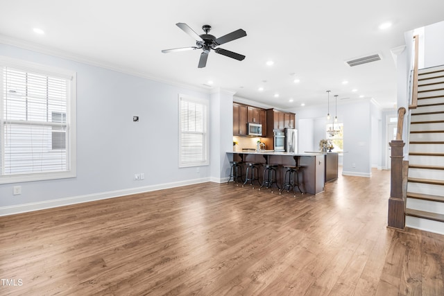 unfurnished living room with ceiling fan, crown molding, and dark wood-type flooring