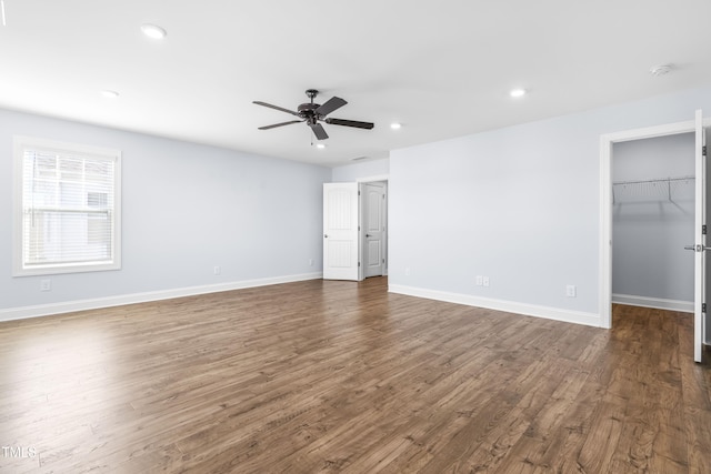 unfurnished bedroom featuring a closet, a walk in closet, dark hardwood / wood-style floors, and ceiling fan