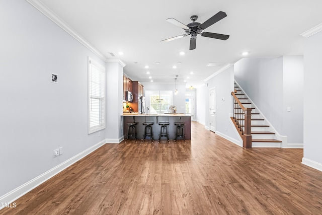 kitchen with a kitchen bar, kitchen peninsula, crown molding, and dark hardwood / wood-style floors