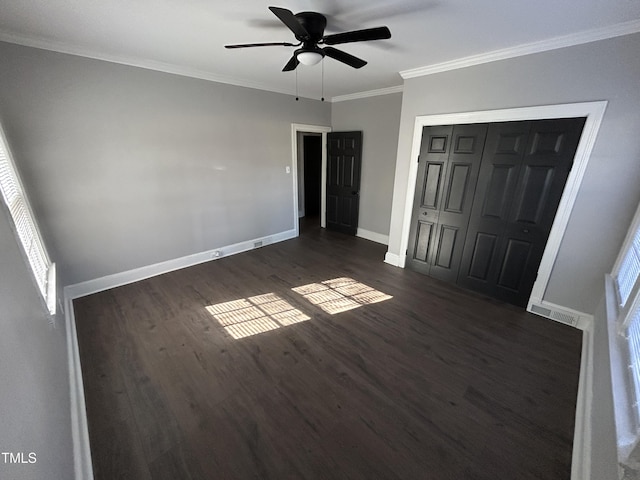 unfurnished bedroom featuring ceiling fan, dark hardwood / wood-style flooring, crown molding, and a closet