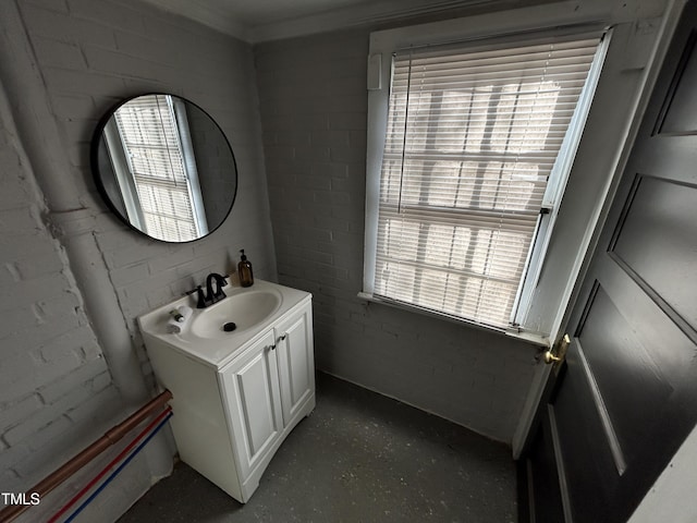 bathroom featuring plenty of natural light, vanity, and brick wall