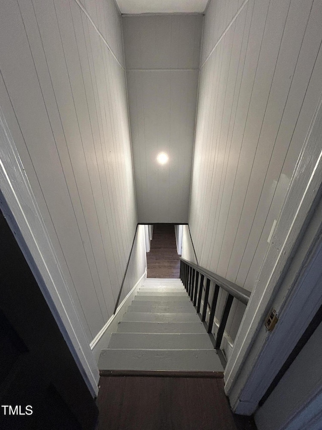 staircase featuring wooden walls and hardwood / wood-style floors