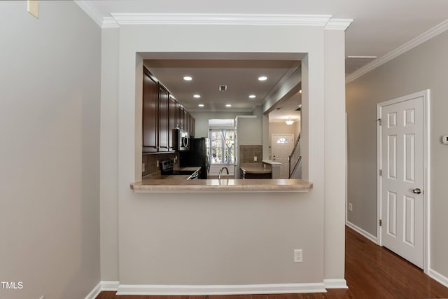 kitchen featuring kitchen peninsula, appliances with stainless steel finishes, tasteful backsplash, crown molding, and dark wood-type flooring