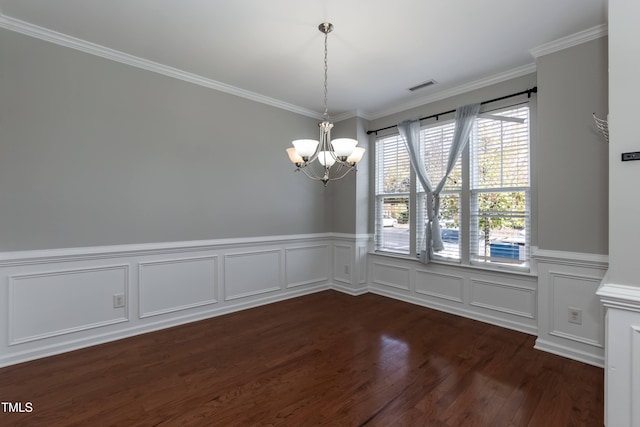 unfurnished dining area featuring dark hardwood / wood-style floors, ornamental molding, and an inviting chandelier