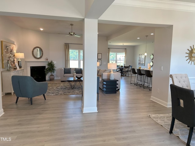 living area with recessed lighting, a fireplace, a ceiling fan, baseboards, and light wood-type flooring