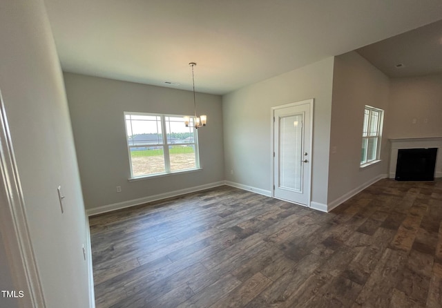 unfurnished dining area with a fireplace, baseboards, dark wood finished floors, and a notable chandelier