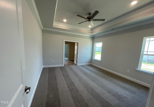 unfurnished bedroom featuring ornamental molding, dark carpet, a raised ceiling, and baseboards