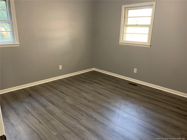 spare room with dark wood-type flooring and plenty of natural light