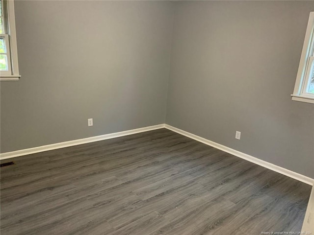 unfurnished room with dark wood-type flooring and a wealth of natural light