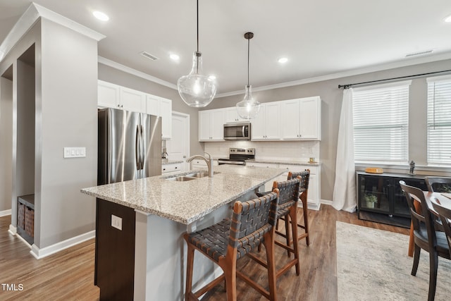 kitchen featuring stainless steel appliances, sink, a center island with sink, white cabinets, and hardwood / wood-style floors