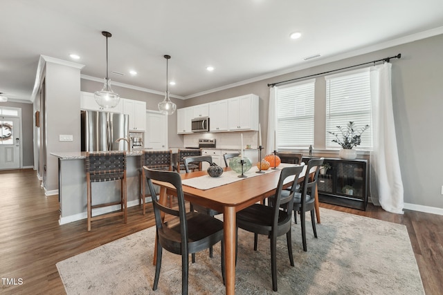 dining room with dark hardwood / wood-style flooring, crown molding, and sink