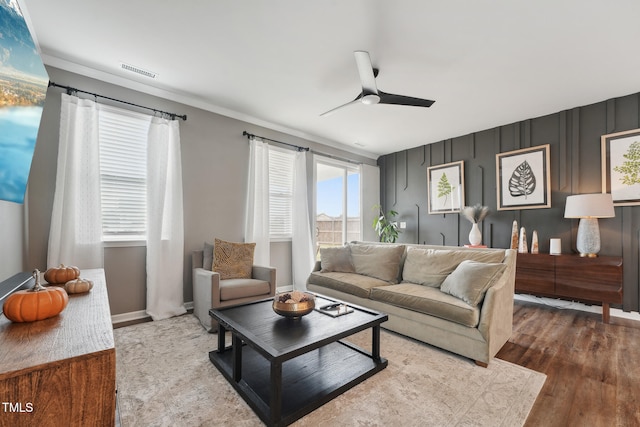 living room with wood-type flooring, ceiling fan, and ornamental molding