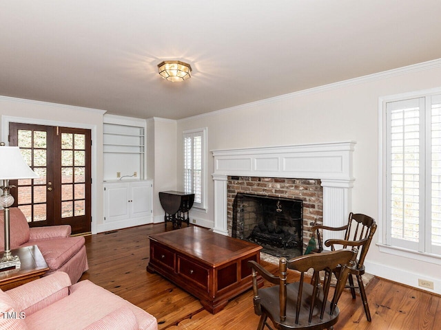 living room with a fireplace, hardwood / wood-style floors, french doors, and crown molding