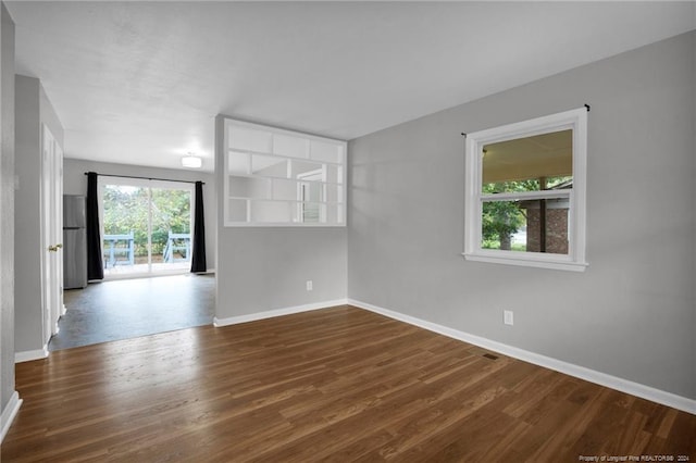 empty room with a healthy amount of sunlight and dark hardwood / wood-style flooring