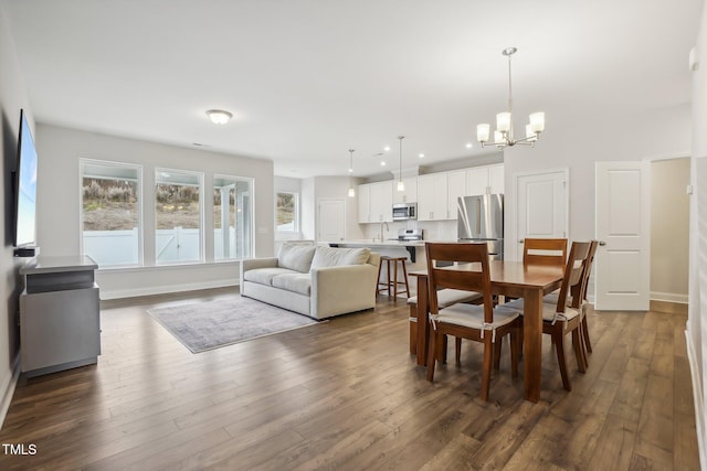 dining space with sink, dark wood-type flooring, and an inviting chandelier