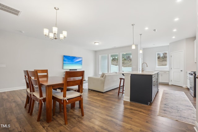 dining area with sink, a chandelier, and dark hardwood / wood-style floors