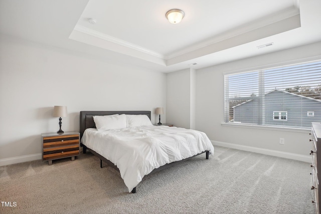 carpeted bedroom featuring a raised ceiling and ornamental molding