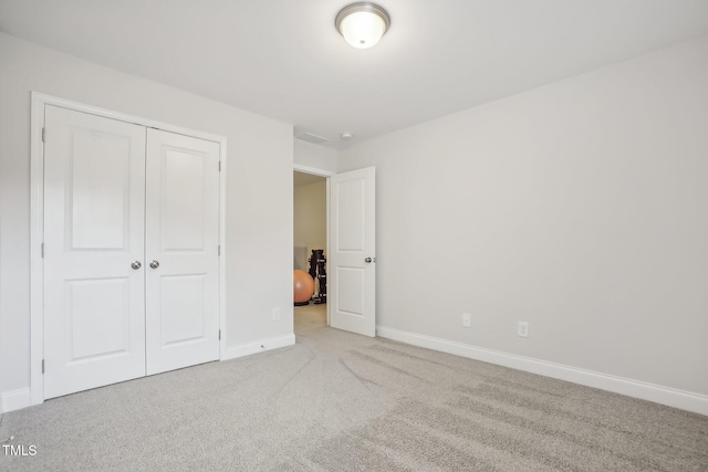 unfurnished bedroom with light carpet and a closet