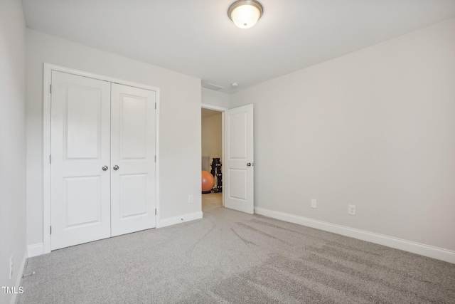 unfurnished bedroom with light carpet and a closet